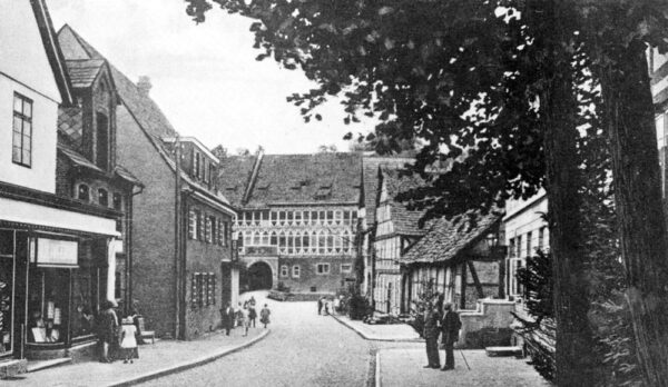 Die Burgstraße mit dem Amtshaus - um 1930: Die Funktion als Geschäfts- und Einkaufsstraße bei der Deckung des täglichen Bedarfs der Bewohner wurde hier erfüllt; Bäckerei Berner, Zeuggeschäft Hagedorn, die Zweigstelle Wesertal, die Schneiderei Neermann, die Apotheke, die Reichspost die Gaststätte “Stadt Hannover” sowie die Amtssparkasse sind hier erkennbar. Mit dem Verlust der Amtsgebäude im April 1945 sowie dem Ausbau der Bundesstarße B83 im Jahre 1965 gingen diese Teile der historischen Bebauung ebenso verloren wie die gewachsenen Anbindung der Burg an den Ort.