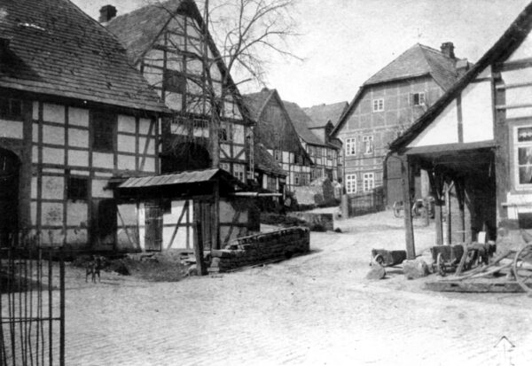 Kreuzungsbereich von Hinterer und Marktstraße: Zeitgenössische Aufnahme aus dem Jahr 1920. Es sind die Fachwerkhäuser der Kötnerstelle Wehrbein, des Schlosser- und Bürgermeisters Bost, des Stellmachers Zaag und Floto mit der “Klenk’schen Schmiede” zu sehen, die bis in die sechziger Jahre als geschlossenenes Ensemble erhalten wurden und als “Gänsemarkt” bezeichnet wurden.