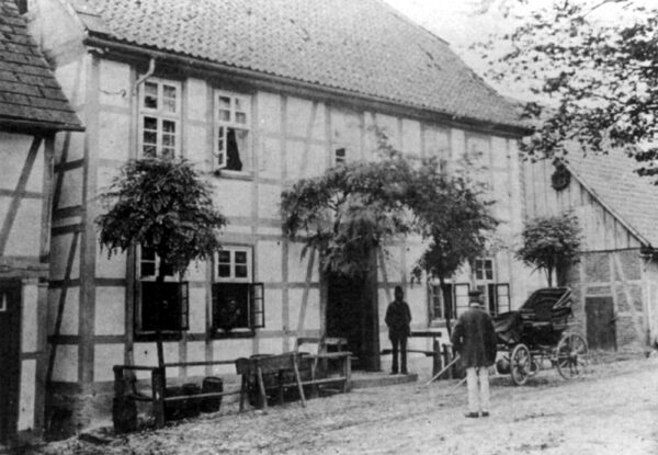 Das Gasthaus zur Krone an einem Ende der Markstraße um die Jahrhundertwende (19. Jh.): Die Kutsche ist angespannt und vor dem Haus stehen die Bierfässer sowie eine Pferdetränke; die Straßenfront wird von Bäumen beschattet.