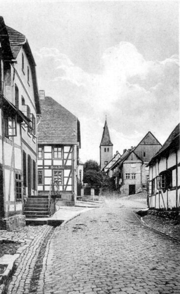 Die Mittelstraße um die Jahrhundertwende (18./19. Jh.) mit der Kreuzung über die Marktstraße: Das Straßenbild in diesem Bereich (unteres Dorf) wird zu dieser Zeit durch die Straßenoberflächenpflasterung mit Kopfsteinpflaster sowie die geschlosene Bebauung mit Fachwerkhäusern geprägt.geprägt.